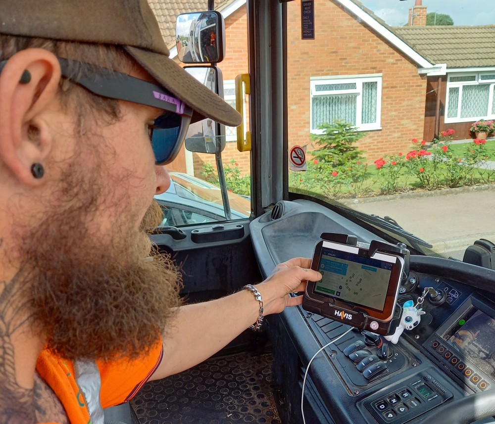 A waste collection crew team member using the in-cab system