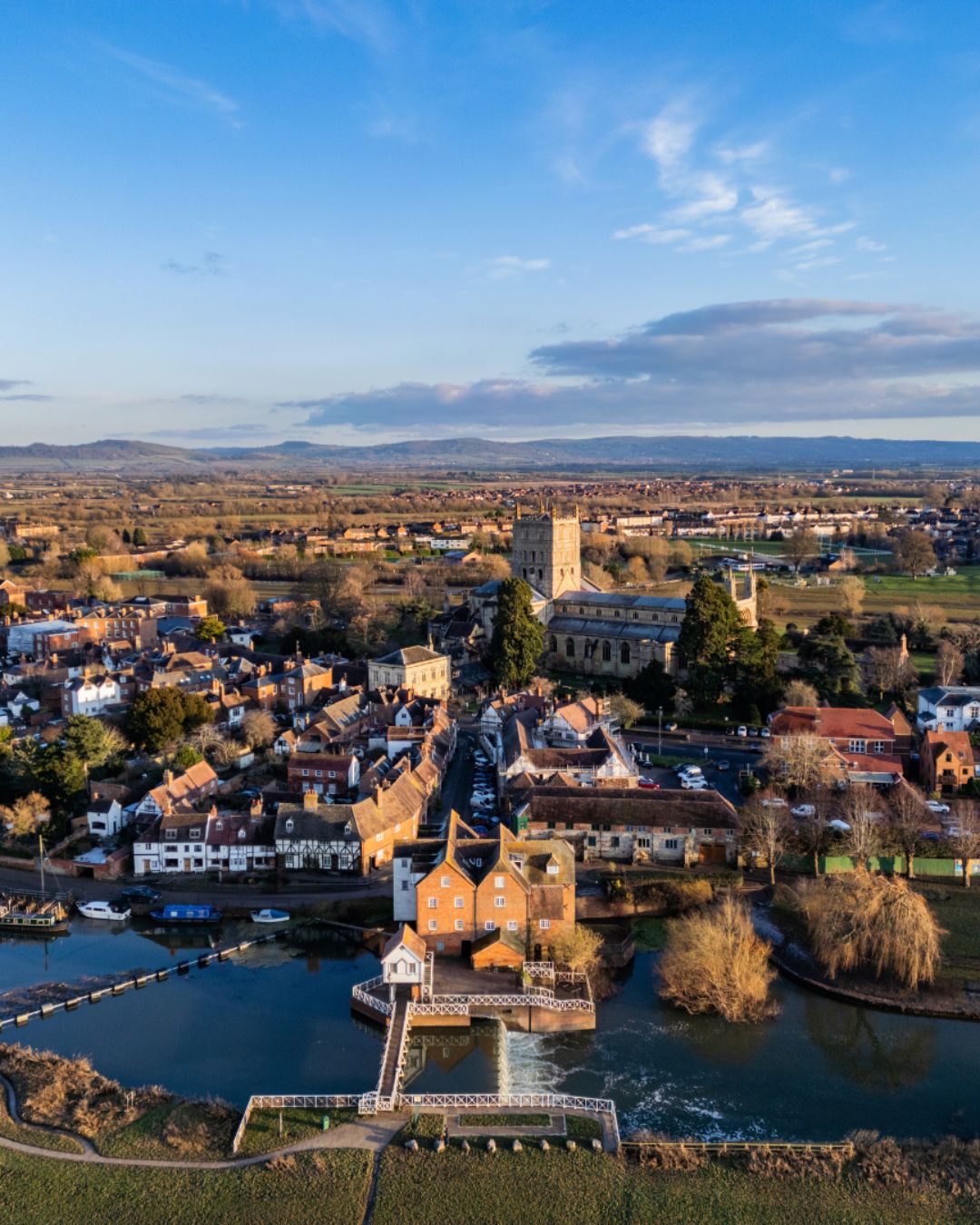 Ariel view of Tewkesbury town on a blue sky day with the Abbey and river featured
