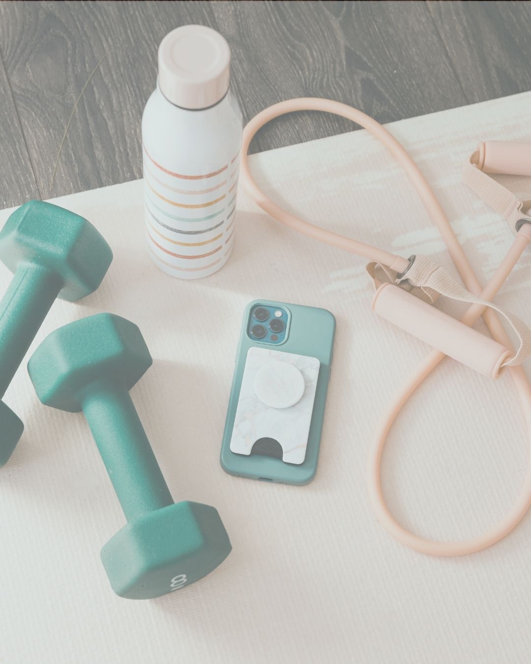 gym equipment with dumbell, skipping rope and water bottle with a phone in the centre