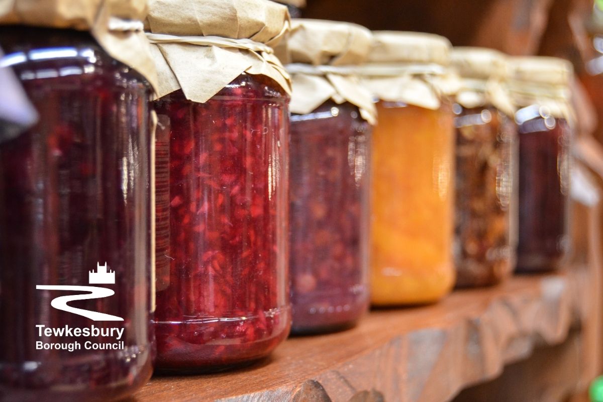A row of preserves on a wooden shelf.