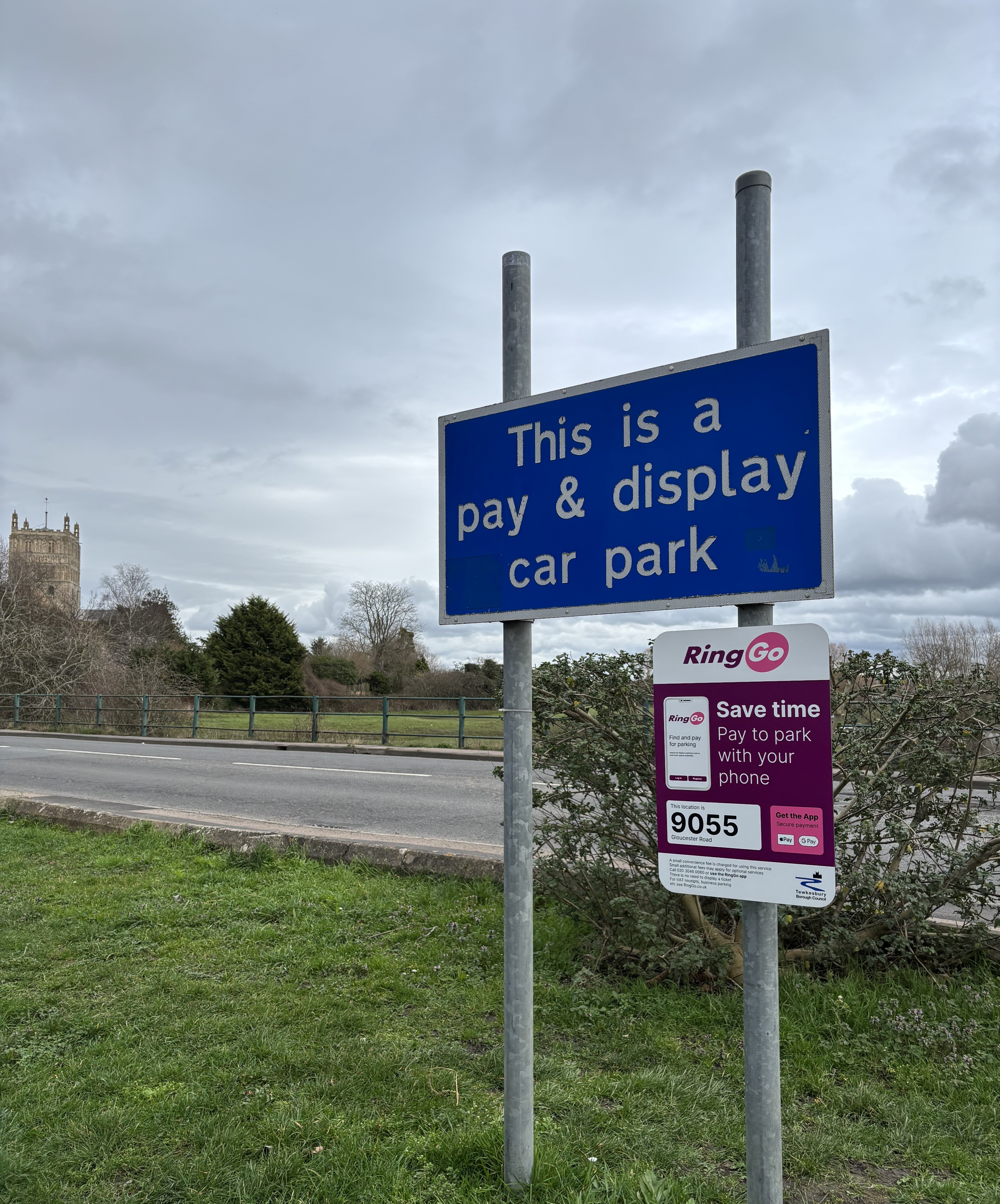 A sign in a car park that is opposite Tewkesbury Abbey the sign reads This is a pay and display car park and a smaller sign with the Ringo app is shown